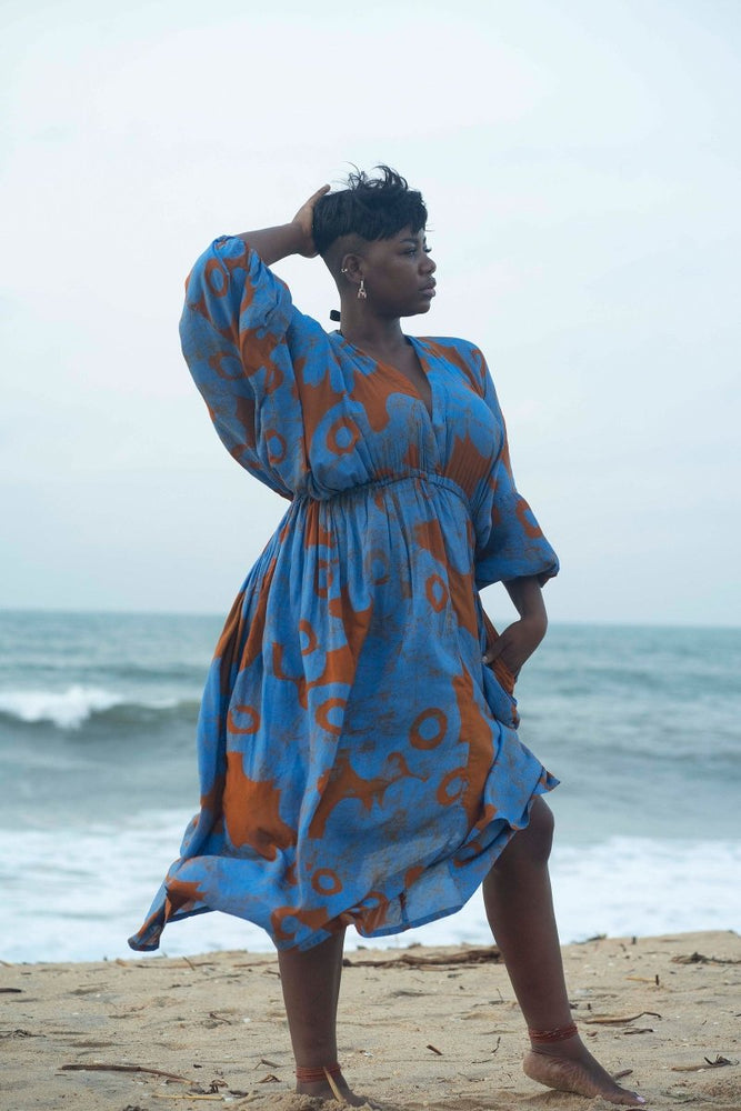 Chic Bating Dress in All Ideas print with batwing sleeves, styled for a casual beachside pose under a cloudy sky.