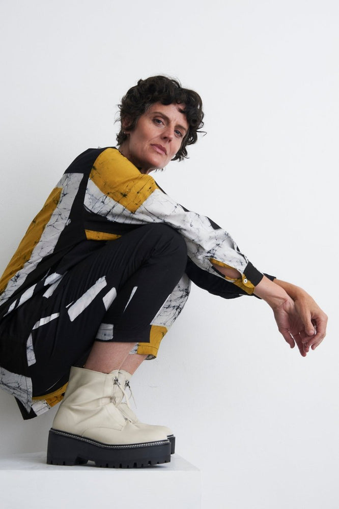 Contemporary Bula Shirt with black lines, white marble patterns, and yellow sections, paired with black pants and platform boots.