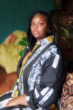 Person in Bula Shirt with black/white and yellow print, against green wall with colorful decor.