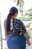 Epo Tie Top in 2 Party System print, back view on balcony, black floral pattern, paired with blue jeans.