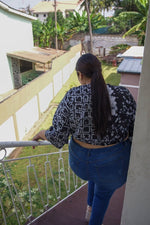 Model walks down stairs in Epo Tie Top in 2 Party System print, back view on balcony, overlooking buildings and greenery.