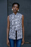 Index Vest in Long Division print with high neckline, button front, and asymmetrical hem, paired with blue jeans.