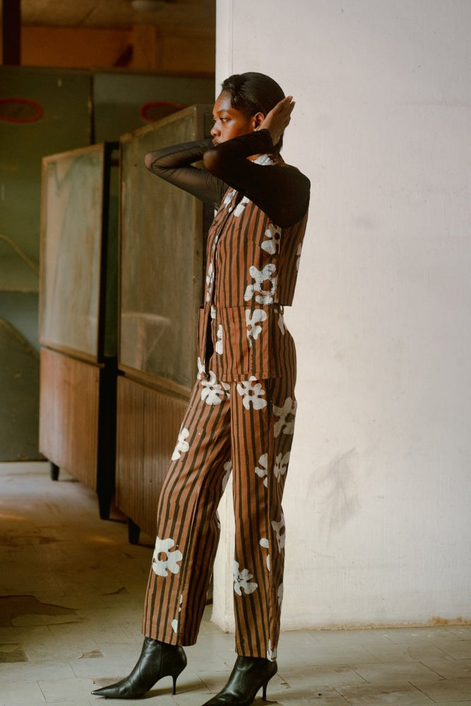 Model in the Index Vest in Ruga print with her arms raised touching her head, wearing black heels.