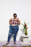 Lupi Top in Tunnel of love styled with blue jeans. Model poses next to white column with flower bouquet against white wall.