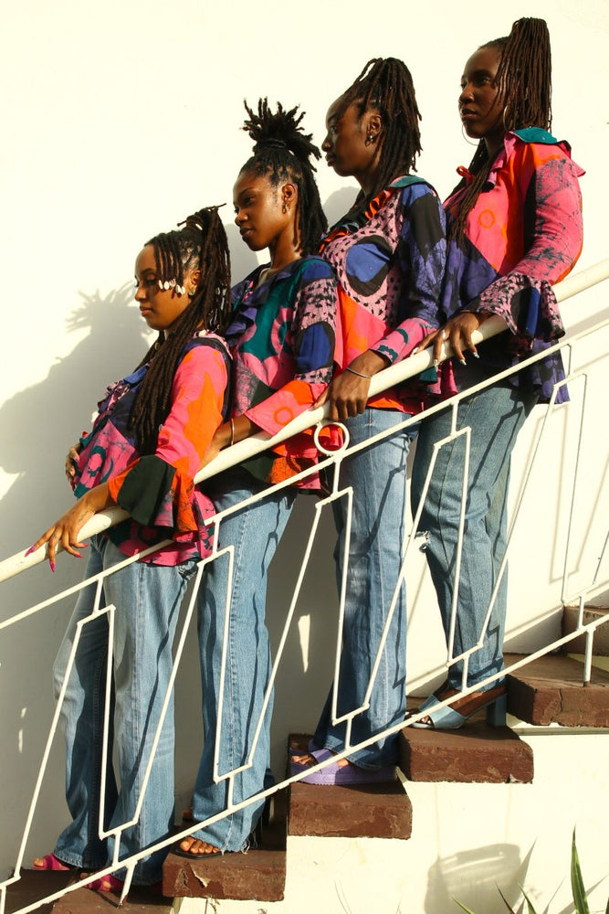 Vibrant Pastiche Clo ensemble on staircase, with sunlit shadows adding depth to the colorful patterns and denim style.