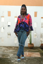Elegant Pastiche Clo blouse in a blend of pink and blue, perfect for outdoor style, with a white architectural backdrop.
