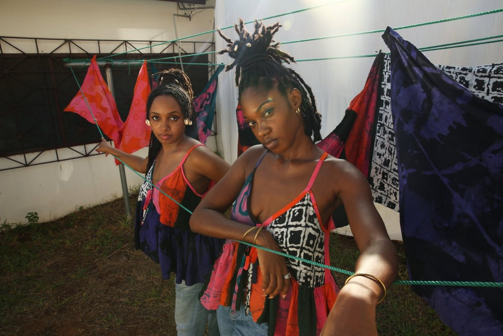 Pastiche Valley’s unique tops against a backdrop of colorful fabrics on a clothesline, capturing a moment of creativity and connection.