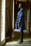 Model in blue and white patterned Press Dress with long sleeves, standing in a sunlit corridor, wearing high-heeled boots.