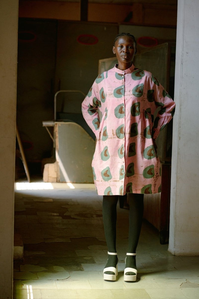 Model standing in a doorway, wearing the long-sleeve Press Dress in Tunnel of Love batik print. 