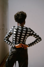 Back view of person wearing Osei-Duro Rift Top in Dominos batik print, long sleeves, against plain background.