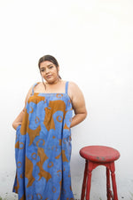 Chic Saya Dress in blue and orange All Ideas print, standing against a plain white backdrop with a red stool.