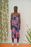 Model wearing the Saya Dress in Pool Party print, paired with white sneakers, standing against a patterned backdrop.