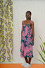 Full-length view of a model wearing the Saya Dress in Pool Party print, standing against a patterned backdrop.