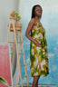 Side view of model in the Saya Dress in Waters print, standing next to a wooden ladder with a basket of flowers.