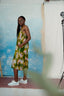 Side view of model wearing the Saya Dress in Waters print, standing in front of a wall with a blue sky and cloud pattern.