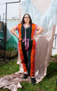 Colorful Accra Jumpsuit with vertical stripes and pink belt, casual pose against a draped fabric backdrop.