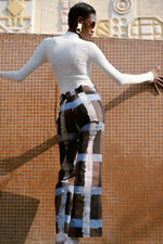 Back view of Veronica Trousers in Highlands batik print, standing in front of an ornate building facade.