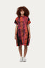 Knee-length Bata Dress in vibrant Carmine batik, with abstract tie-dye pattern and white sneakers.