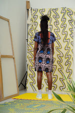 A woman stands before a wall, showcasing the captivating Hocus Pocus print's unique design.
