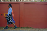 Dynamic Bating Dress ensemble against a red wall, paired with dark boots and a spirited walk.