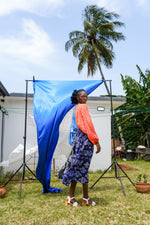 Vibrant Bating Dress with orange top and blue-white patterned skirt, set against an outdoor blue fabric backdrop.