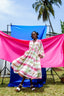 Serene Dreams Bata Dress against a creative blue and pink fabric backdrop, paired with white open-toed shoes.