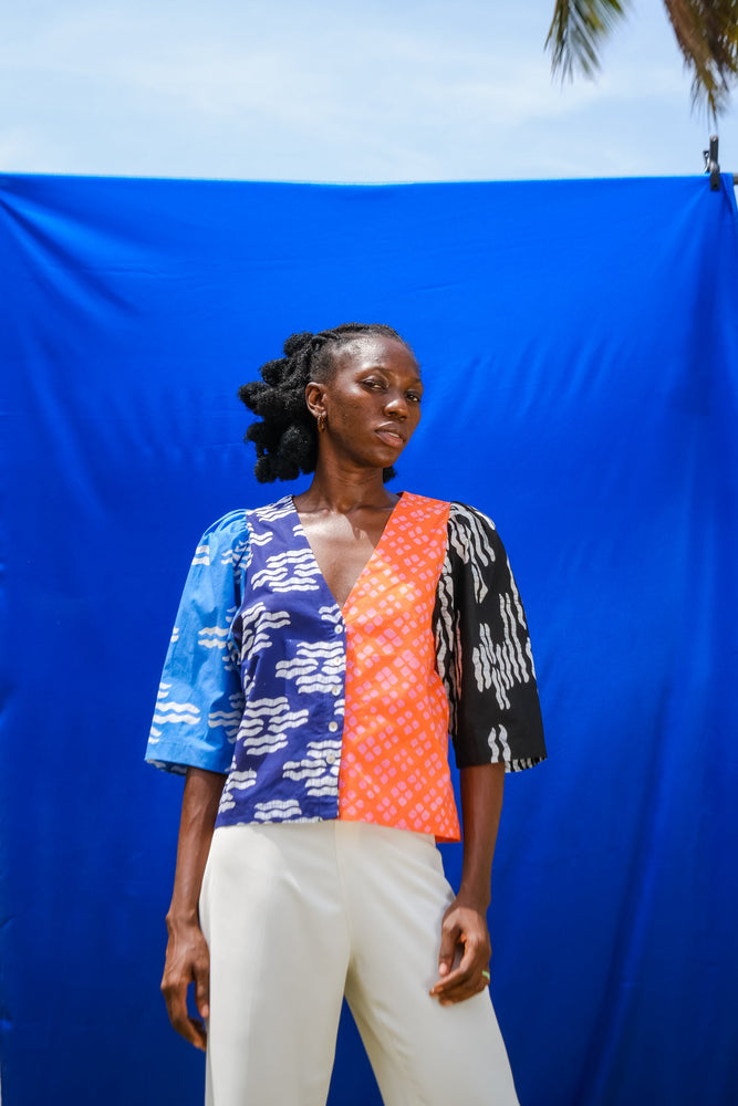 Model stand against blue fabric wearing the Flos Blouse in Directions, a modern and sustainably fashion choice.