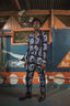 Accra Jumpsuit against artistic mural, showcasing unique Good Signal batik print and golden-detailed shoes.