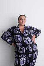 Woman in Accra Jumpsuit with Good Signal print, highlighting drawstring waist and front zipper, against a plain backdrop.