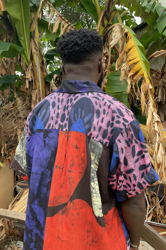 A guy in a vibrant shirt posing by a banana tree. His holiday shirt is all about hocus pocus!
