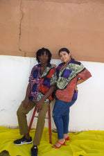 A seated man and a woman in our rayon Holiday shirt in the batik print Hocus Pocus.