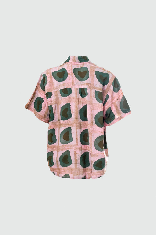 A back view ghost mannequin image of the same shirt, batiked pink with dark green and black organic shapes like avocados.