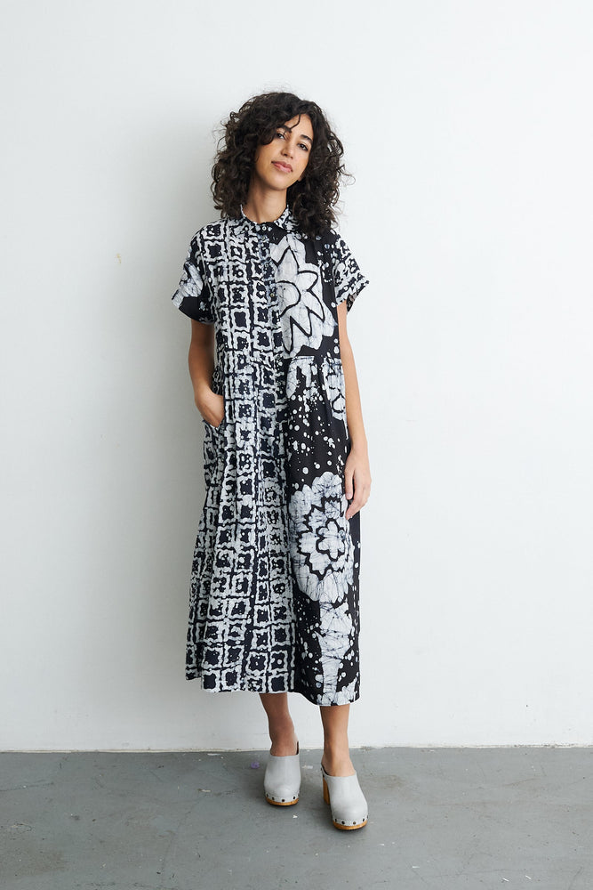 Elegant Imperium Dress with bold 2 Party System print, short sleeves, and mid-calf length, paired with chic white heels.