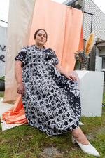 Imperium Dress in 2 Party System print, styled for an artistic outdoor setting with vibrant orange and white backdrops.