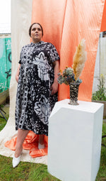Imperium Dress in 2 Party System print, styled for an artistic outdoor setting with vibrant orange and white backdrops.