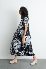 Dynamic Imperium Dress in 2 Party System print, mid-step movement, paired with white clogs, against a minimalist backdrop.