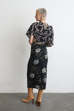 Rear view of Katharos Dress in Nap Time print, showcasing silk wrap patterned top and floral wrap skirt with tan boots.