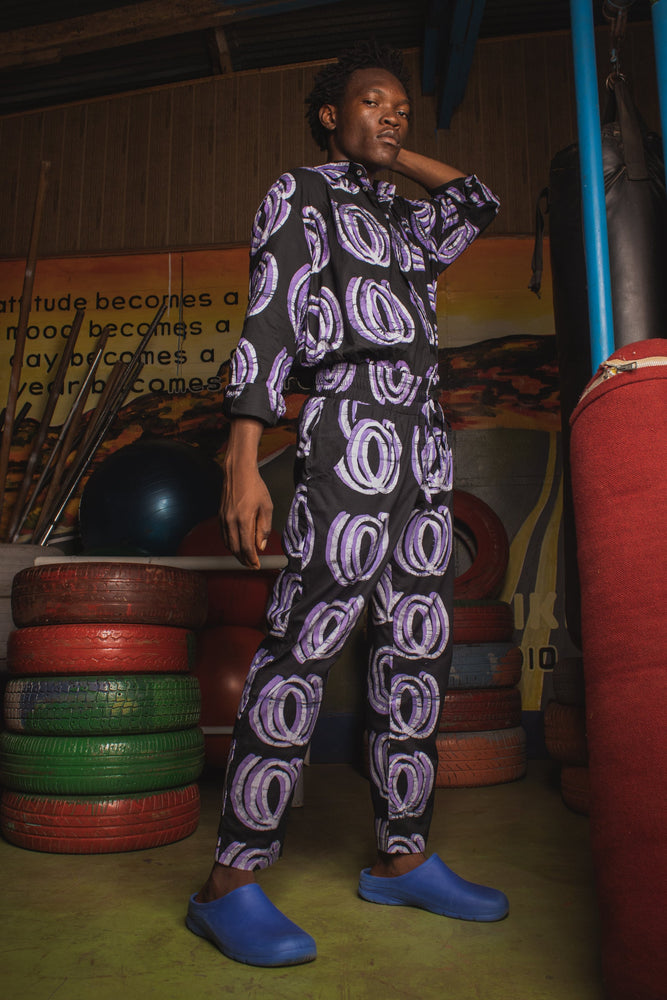 Man wearing the Kpong Trousers in Good Signal print, top and pants set, next to punching bag, ready for an active day.