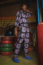 Man wearing the Kpong Trousers in Good Signal print, top and pants set, next to punching bag, ready for an active day.