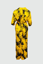Long Letsa Dress in yellow with bold black leaf print, wrap style with waist tie, and long sleeves against a grey background.