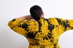 Rear view of Letsa Dress in Aden print, person with arms out displaying the long sleeves and pattern, against a white wall.