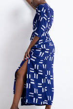Letsa Dress in Middle Path print, side view, white line pattern on blue fabric, with hand lifting dress for leg reveal.
