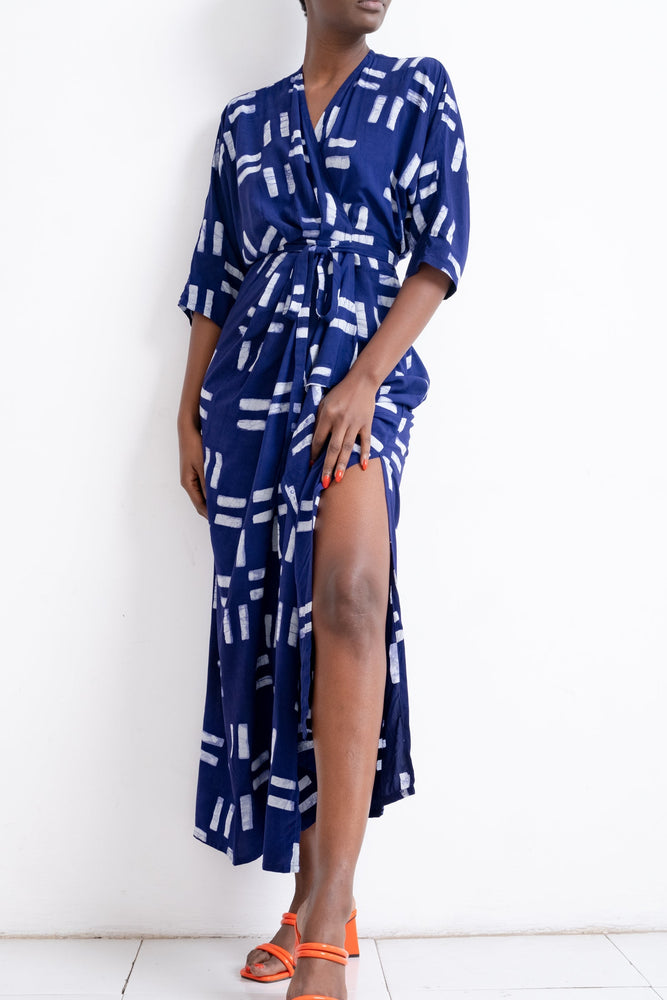 Letsa Dress in Middle Path print, midi length with abstract white pattern on blue, wrap design, and orange strappy heels.