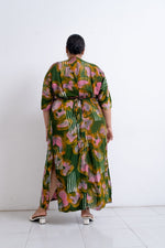 Rear view of Letsa dress showcasing the vibrant Waters print and green base, paired with white shoes.