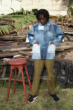 Man poses with wood pile wearing a jacket made from locally sourced denim patchwork, a sustainable solution to textile waste.
