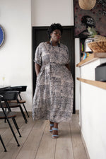 Nonna Dress in Snakebite, spotted print with short sleeves, styled with blue open-toed shoes and indoor decor.