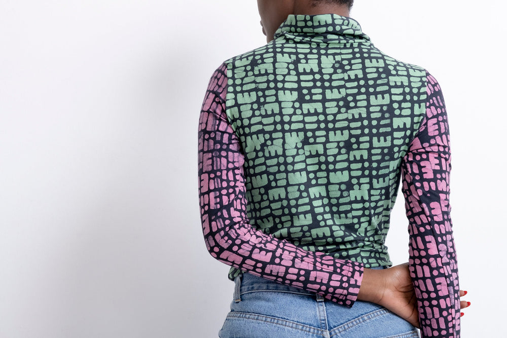 High-necked Stricta Turtleneck with vibrant green and pink pattern on dark background, paired with classic blue jeans.