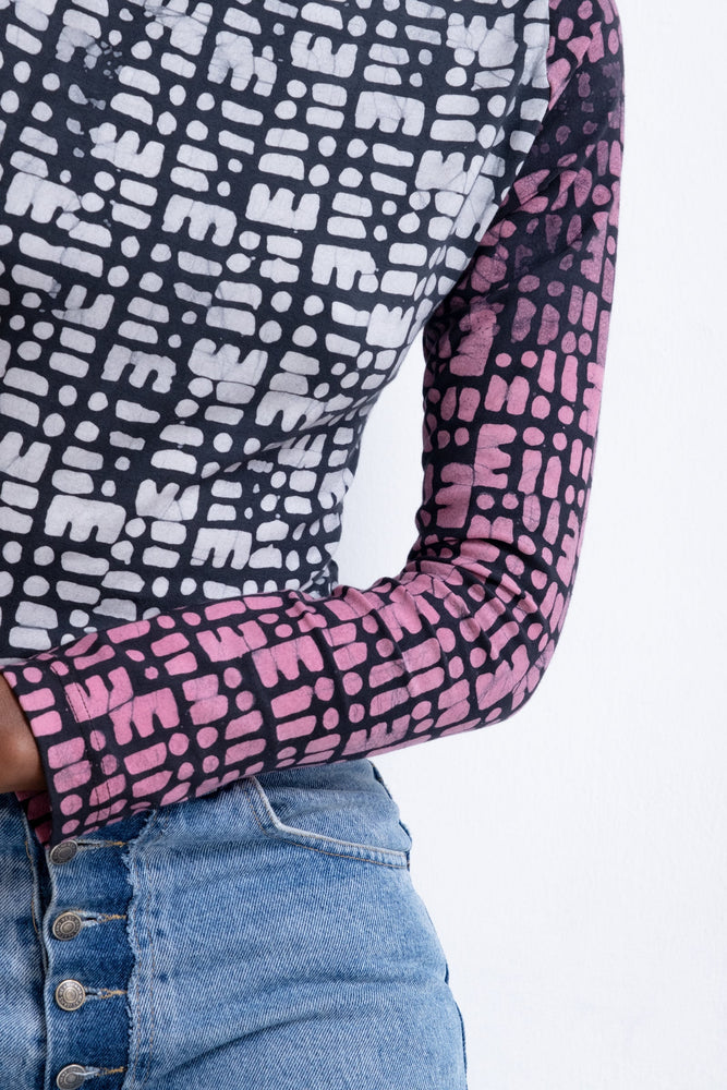 Long-sleeved top with black and white body pattern and pink-black sleeves, paired with blue denim jeans.