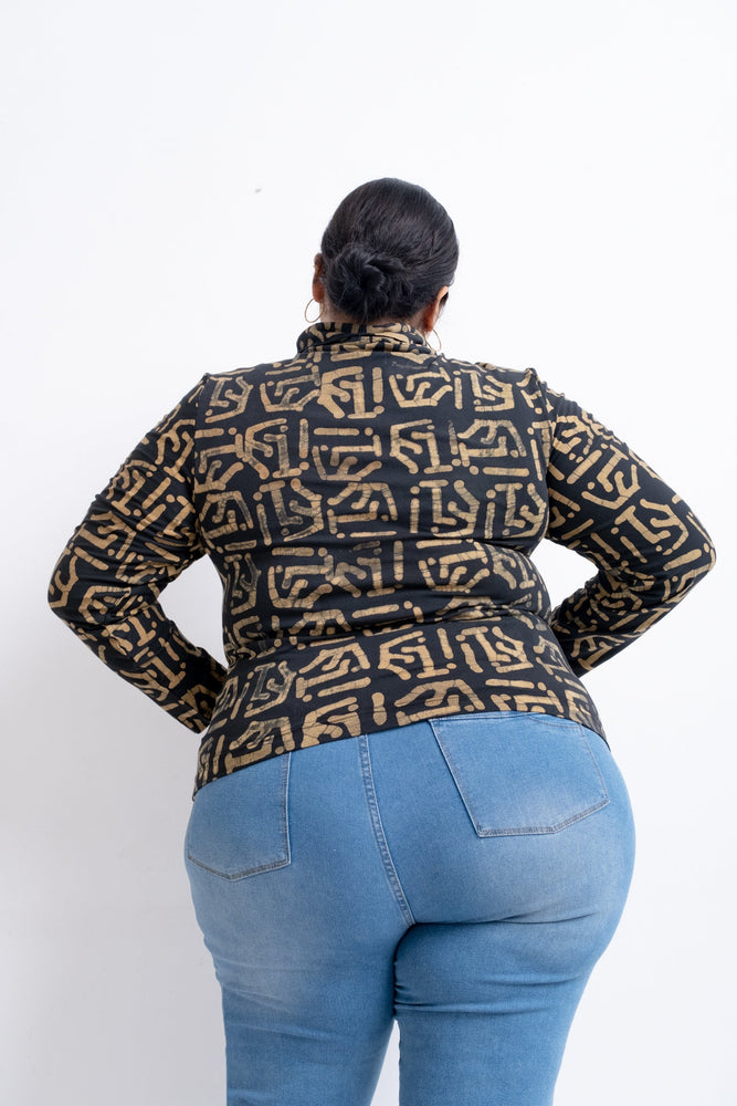 Rear view of a person in a black and gold patterned top with long sleeves, paired with blue jeans.