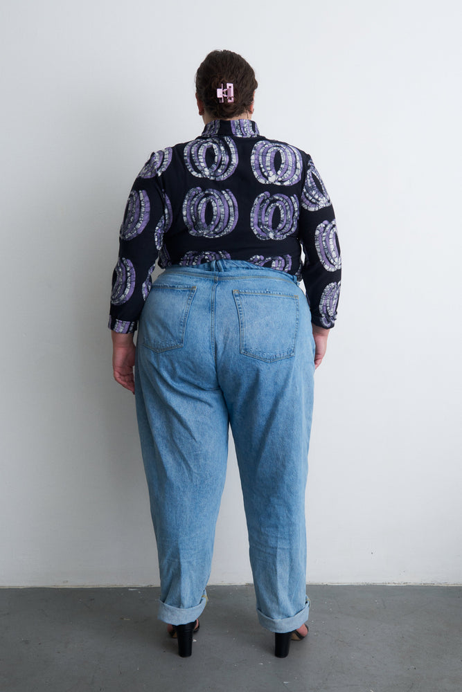 Back view of the Stricta Turtleneck in Good Signal and blue jeans, showcasing the unique print and color contrast of the top.